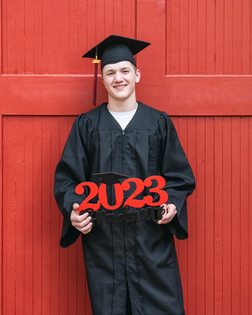 A high school senior graduate poses in cap and gown at Columbia Riverfront Park. Senior portraits often feature the year of graduation as shown here.