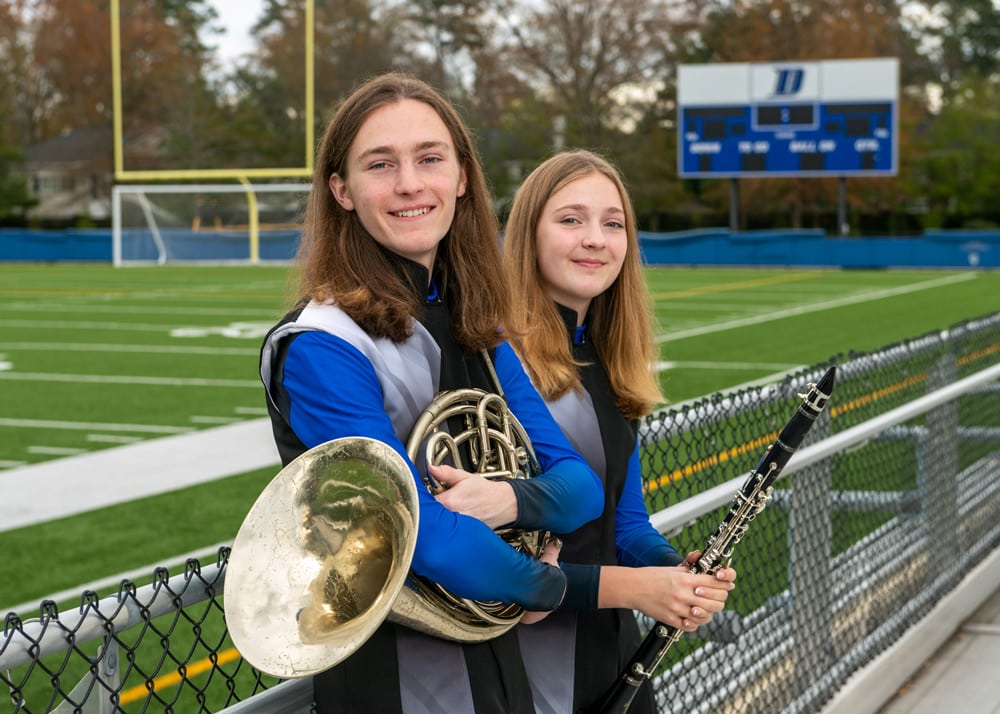 A brother and sister in the Dreher High School marching band pose for a senior photo session at the football field.